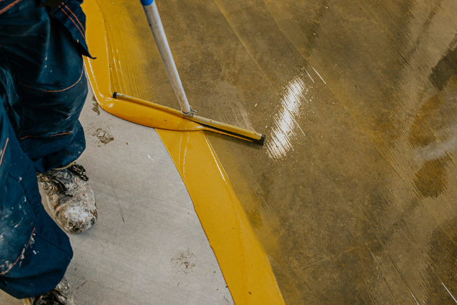 Worker coating floor with self-leveling epoxy